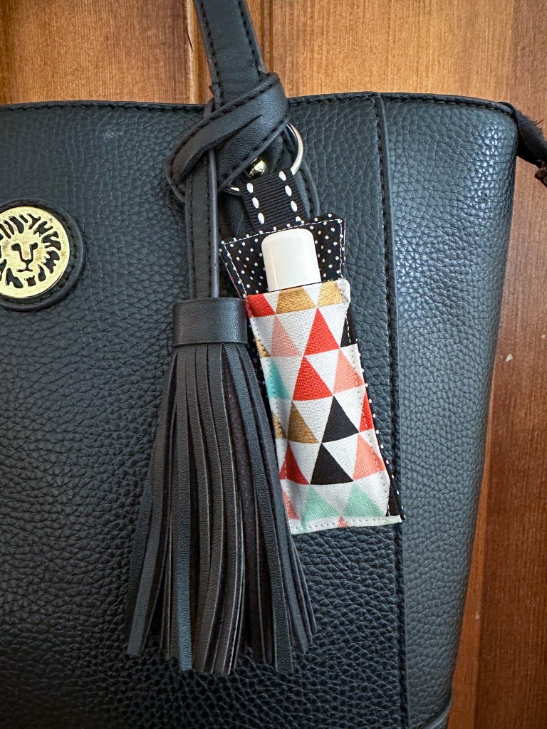 Close up of a DIY fabric lip balm holder clipped to the outside of a purse