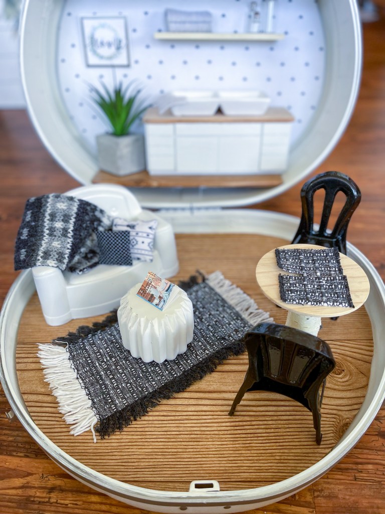 Kitchen, living room and dining room in a dollhouse made in a vintage suitcase.