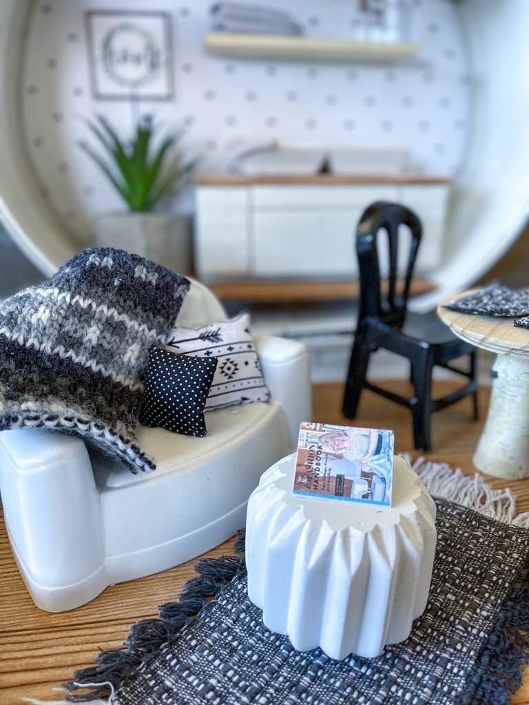 close up of a cozy miniature couch in the tiny living room of a dollhouse made from a vintage suitcase