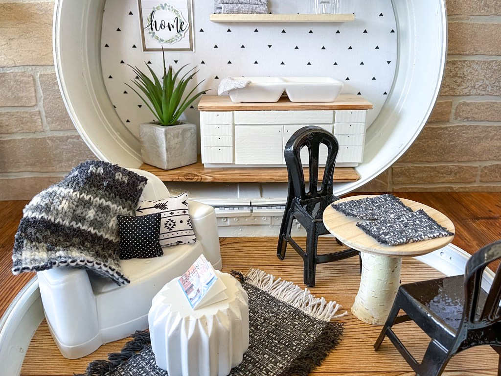 Kitchen, living room and dining room in a dollhouse made in a vintage suitcase.