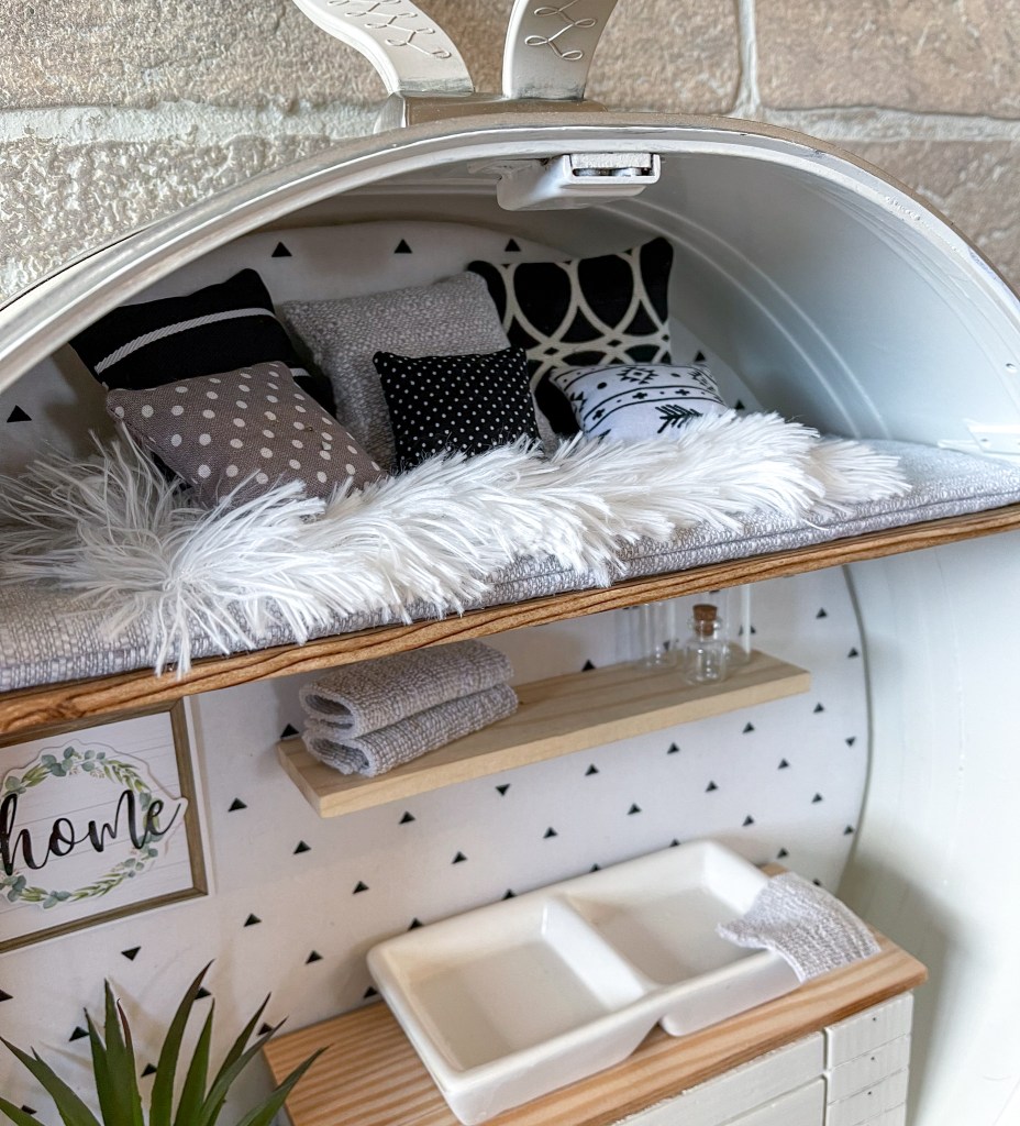 close up of a cozy miniature loft filled with pillows in a dollhouse made in a vintage suitcase