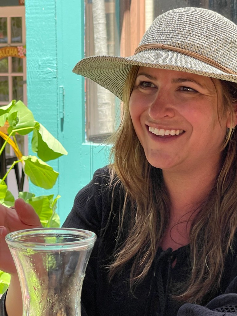 Close-up image of my daughter smiling brightly in Lahaina, Hawaii, her face shaded by her perfect sun hat, capturing a moment of pure joy and island beauty.