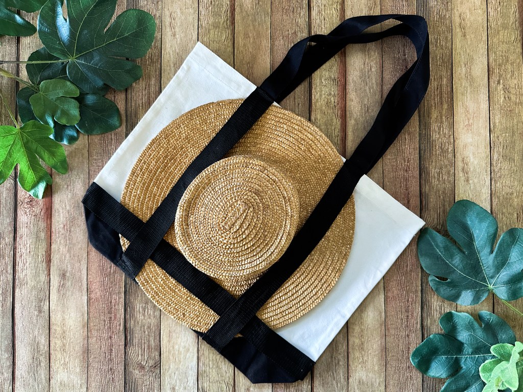 Overhead view of a stylish sun hat neatly tucked into a handmade tote bag, perfectly arranged for a chic summer outing.